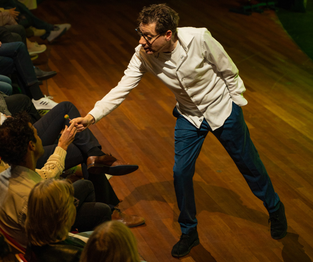 Ewald als Maarten buigt zich naar de eerste rij en geeft iemand in het publiek een lolly